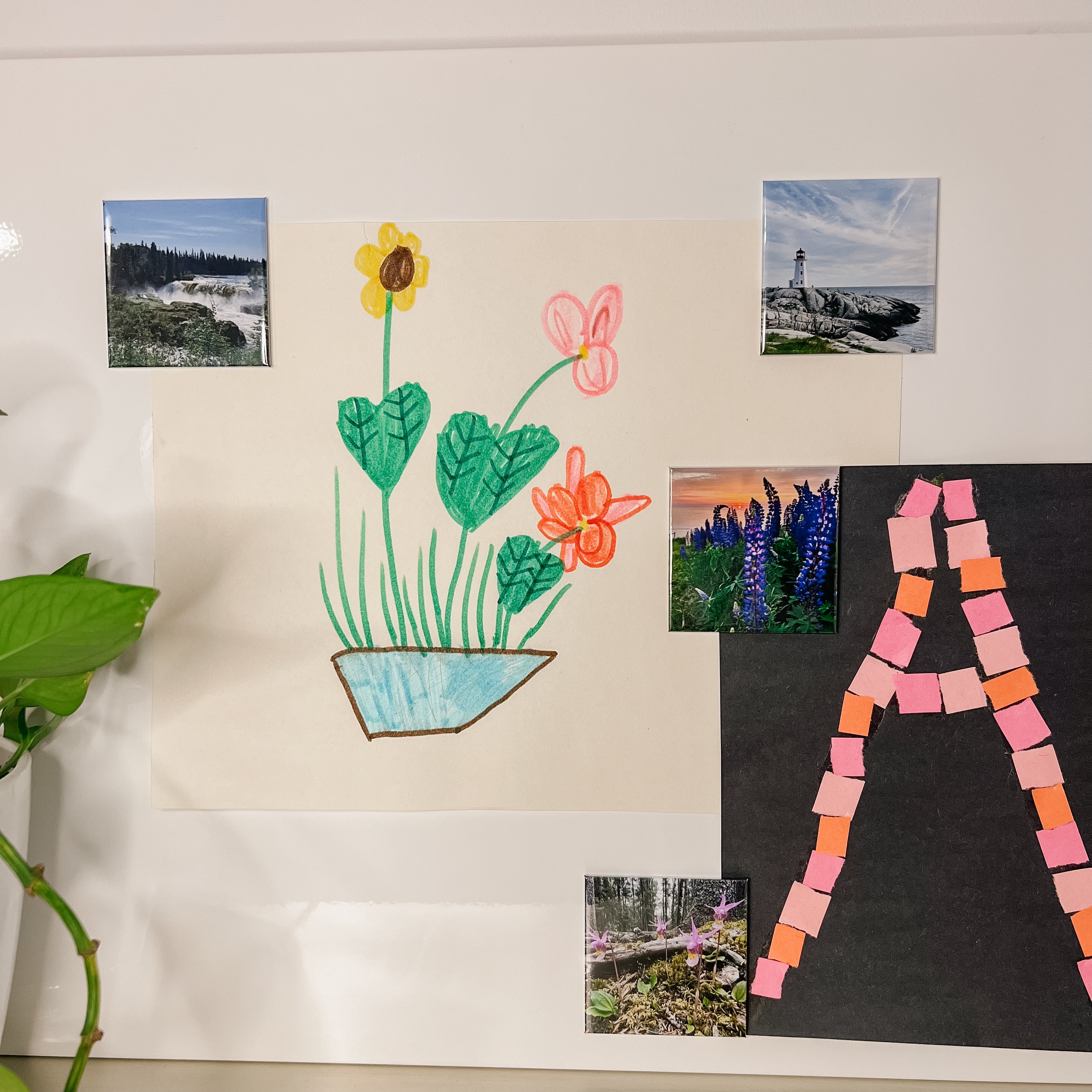 Children's artwork on a magnetic surface being held up with custom travel photo magnets